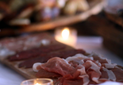 Samples of prosciutto and other cured meats await neighbors on a candlelit table. (Robert Morris, UptownMessenger.com)