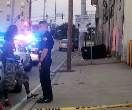 An officer detains a man near the scene of a fatal shooting Tuesday evening in the 400 block of Felicity Street. (Robert Morris, UptownMessenger.com)
