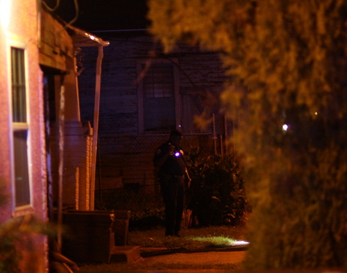 An officer looks for evidence in a South Saratoga yard after the shooting. (Robert Morris, UptownMessenger.com)