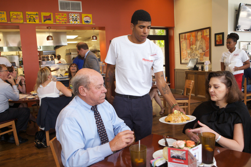 Reginald Cannon serves a fish entree to a customer at Cafe Reconcile's Central City facility on Thursday afternoon. Caf Reconcile works to resolve the deeply ingrained social ills of poverty, violence, and neglect by providing at-risk young people, ages 16 to 22, with the skills and confidence necessary to get and retain career-track jobs in New OrleansÕ thriving hospitality sector. (Sabree Hill, UptownMessenger.com)