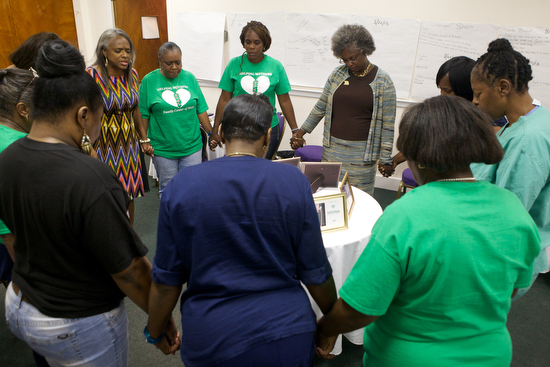The members of "Helping Mothers Heal" gather in a prayer circle at one of their weekly meetings on September 26, 2013. Helping Mothers Heal is a group of mothers who have lost a child to violence. (Sabree Hill, UptownMessenger.com)