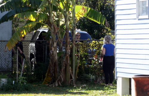 Police speak to neighbors on Dec. 18, 2013, after a large SUV was found ditched in an Adams Street backyard following a deadly robbery at a nearby bank. (Robert Morris, UptownMessenger.com)