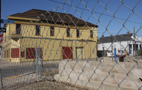 The site of the former Martin Wine Cellar on Baronne Street is still surrounded by chain-link fence, but the new roof on the old New Orleans Bicycle Club building can be seen behind it. (Robert Morris, UptownMessenger.com)