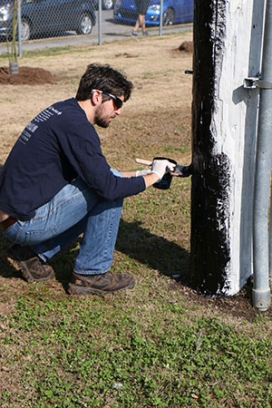 Jon Skvarka, director of Rebuilding Together, repaints a light post at A.L. Davis Park. (photo by Zach Brien for UptownMessenger.com)
