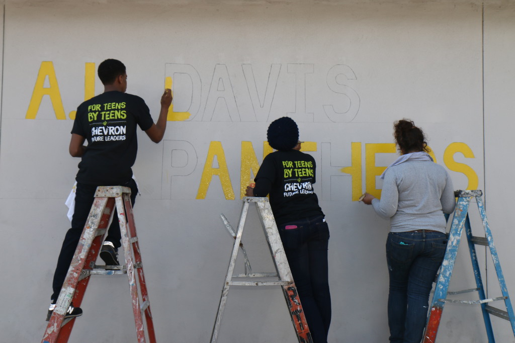 Tyler Johns, left, Shanay Haywood, center, and Rachel May, right, paint "A.L. Davis Panthers" on the outside of A.L. Davis park. (photo by Zach Brien for UptownMessenger.com)