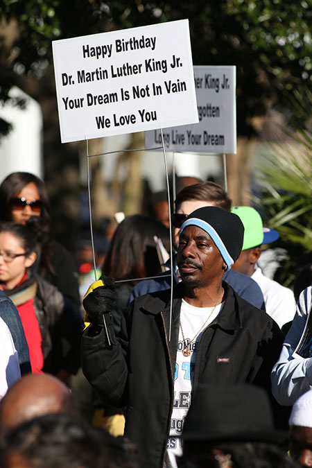 Onlookers hold up commemorative signs in honor of Martin Luther King Jr.