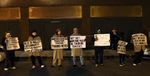 Satiric signs await the Phunny Phorty Phellows, while most revelers crowded the streetcar barn for its relative warmth. (Robert Morris, UptownMessenger.com)