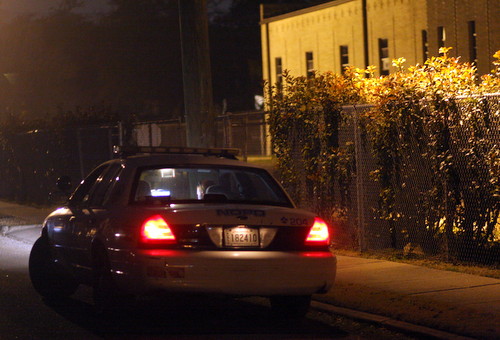 A police officer parked on Willow Street near Nashville works on a report following a robbery call Sunday evening. (Robert Morris, UptownMessenger.com)