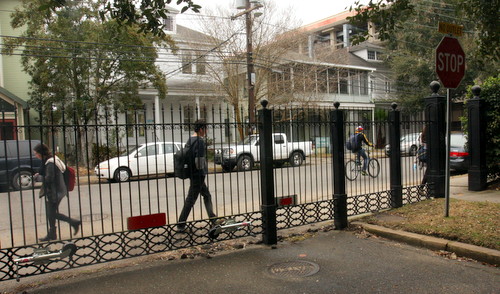 Pedestrians pass by the Newcomb Boulevard fence in early February. (UptownMessenger.com file photo)