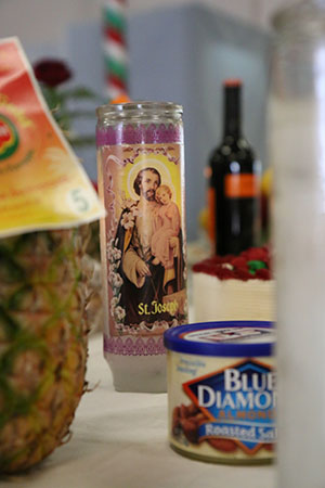 St. Joseph candle among food offerings at De La Salle's St. Joseph altar. (Zach Brien, UptownMessenger.com)