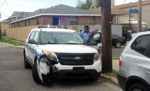 An officer inspects damage to a police SUV on Clara Street following the pursuit. (Robert Morris, UptownMessenger.com)