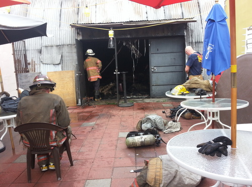Firefighters cool down on the back patio of the Rendon Inn after extinguishing the blaze inside Hangar 13 next door. (Robert Morris, UptownMessenger.com)