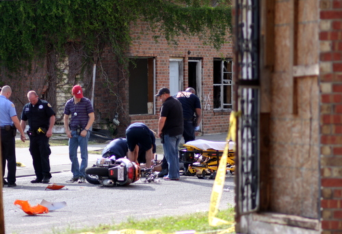 Paramedics tend to a motorcyclist injured near a shooting scene on Fourth Street in Central City. (Robert Morris, UptownMessenger.com)