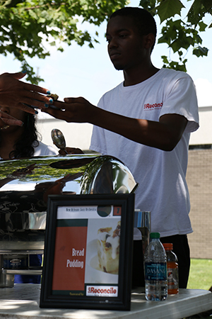 Joshua Keys serves complimentary bread pudding from Cafe Reconcile. (Zach Brien, UptownMessenger.com)