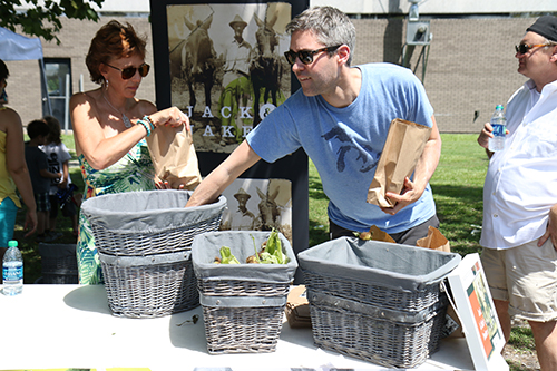 Jennifer Burg (left) and Daniel Momont (right) of Jack and Jake's organic food market pack bags of fresh produce. (Zach Brien, UptownMessenger.com)
