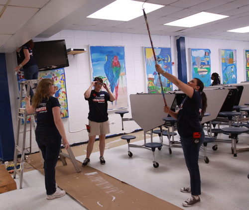 Volunteers paint the Benjamin Banneker cafeteria walls around murals left from the former school. (Robert Morris, UptownMessenger.com)