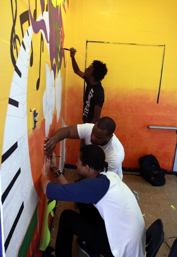 Volunteers paint a mural in a third-floor stairwell at the former Benjamin Banneker campus. (Robert Morris, UptownMessenger.com)