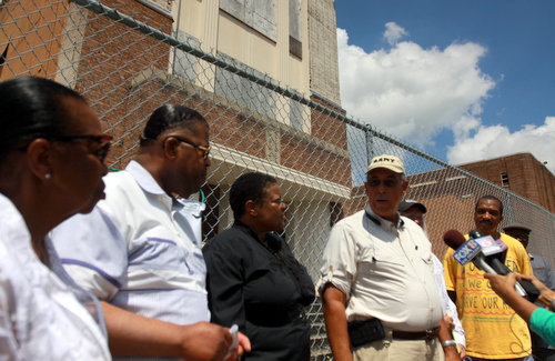 Retired Lt. Gen. Russell Honore (center) and other advocates discuss contamination in the soil at the former Booker T. Washington site in front of what remains of the former school in September 2014. (Robert Morris, UptownMessenger.com)