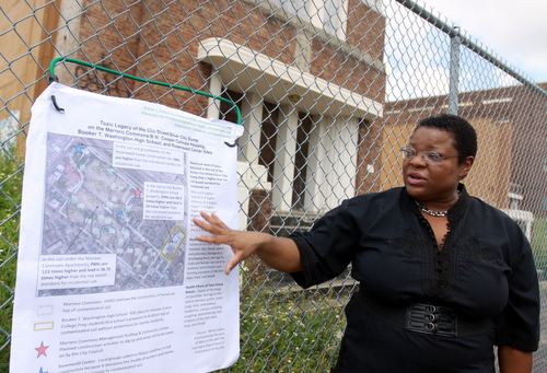 Attorney Monique Harden points to areas of contaminated soil around a map of the Booker T. Washington site on the fence in front of the school. (Robert Morris, UptownMessenger.com)