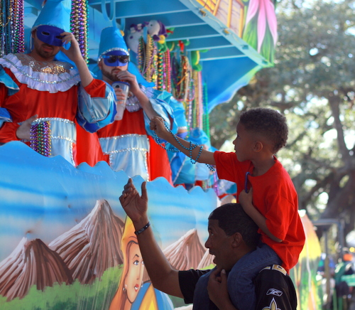 A spectator catches beads during the Krewe of King Arthur parade. (Robert Morris, UptownMessenger.com)