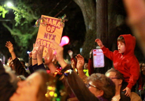 Spectators held up large signs and small children to attract throws from Nyx. (Robert Morris, UptownMessenger.com)