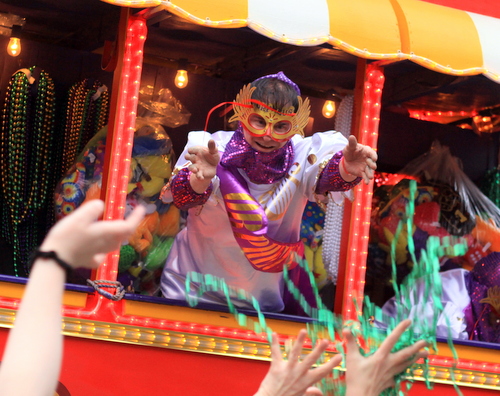 A rider in the Krewe of Orpheus throws beads into the Napoleon Avenue crowd.