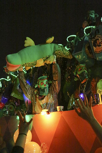 A rider on the "Bacchagator" float teases the crowd with a giant plush alligator. (Zach Brien, UptownMessenger.com)