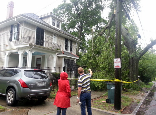 A homeowner in the 1200 block of Lowerline examines a power line pulled down by a falling tree branch in his front yard during Monday morning's storms. (Robert Morris, UptownMessenger.com)