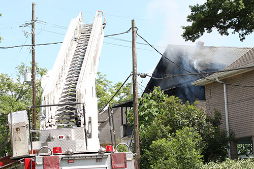 Firefighters use a ladder truck to help put out the fire at 5940 Freret. (Zach Brien, UptownMessenger.com)