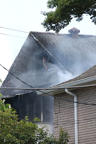 Smoke blows from the roof of the house at 5940 Freret. (Zach Brien, UptownMessenger.com)