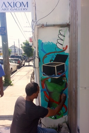 Bryan Brown paints a mural at the new Axiom Art Gallery on Freret Street in early June. (Robert Morris, UptownMessenger.com)