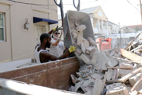 Traelle Nobel, left, and Tre Bullard, right, dump debris from the home into a dumpster once the movers left. (Zach Brien UptownMessenger.com)