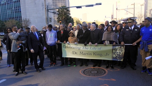 U.S. Rep. Cedric Richmond (left), Mayor Mitch Landrieu and others pause with the banner at the front of the parade. (Robert Morris, UptownMessenger.com)