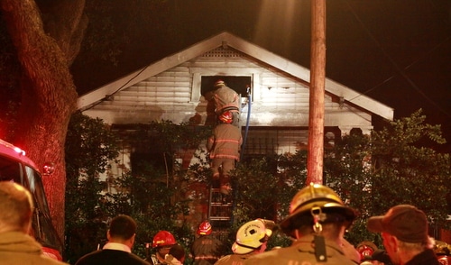 Firefighters look for hotspots in the attic of 1019 Louisiana Avenue on Saturday morning. (Robert Morris, UptownMessenger.com)