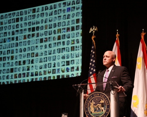 New Orleans Mayor Mitch Landrieu speaks at Tulane University while a projector screen displays the faces of victims of violence in the city. (Robert Morris, UptownMessenger.com)