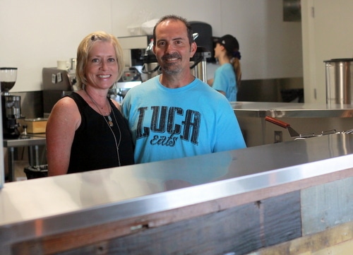 Ellen and Darryl Cortello stand behind a counter made of salvaged wood at Luca Eats. (Robert Morris, UptownMessenger.com)