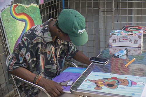 Da'Roll Mitchell paints some artwork at his booth at Roux Carre during First Fridays on the Boulevard on July 1. The event highlighted businesses on Oretha Castle Haley and included drink and food specials, art exhibits and live music.