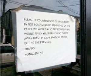 A sign in the front door of TJ Quills urges patrons to respect the neighborhood. (Robert Morris, UptownMessenger.com)