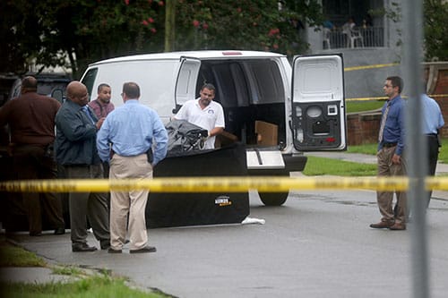 Workers from the coroners office load a body into after a fatal shooting in the 2200 block of Peniston street uptown on Thursday. (Zach Brien, UptownMessenger.com)