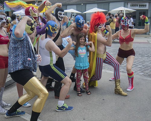 Vivian O'Brien flexes with members of El Lucha on Oak street before the parade. The Krewe of O.A.K. celebrated the 30th anniversary of Mid Summer Mardi Gras with the theme "Get Wet". (Zach Brien, UptownMessenger.com)