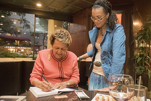 Sybil Morial, left, signs a copy of her book, Witness to Change) for Lishunda Franklin, right. Morial read selections from her book and signed copies at Poseidon restaurant on Saint Charles avenue. (Zach Brien, UptownMessenger.com)