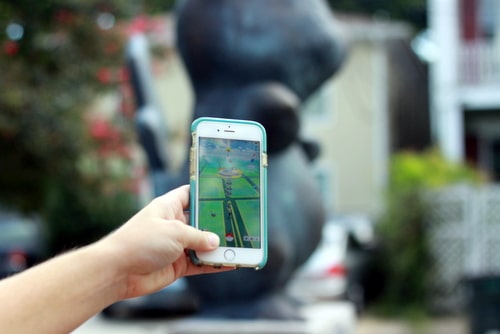 Madeline Dickson checks out the Pokemon gym at the Pikachu statue on her phone. (Robert Morris, UptownMessenger.com)