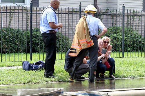 A fire is underway on the 4220 block of S. Rocheblave in Broadmoor. It is a 3-alarm fire and has consumed 2 homes on the block. A woman is consoled by fire officials. (Zach Brien, UptownMessenger.com)